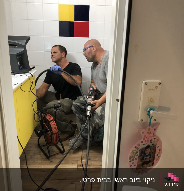 שני אנשים עובדים עם ציוד אינסטלציה בחדר אמבטיה